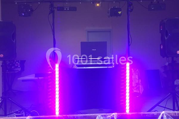 Équipement de sonorisation et éclairage avec lumières violettes, ordinateur portable et haut-parleurs en intérieur.
