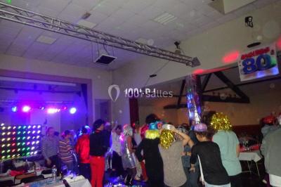 Un DJ mixe derrière une table éclairée de lumières LED violettes, avec un mur décoratif en arrière-plan.