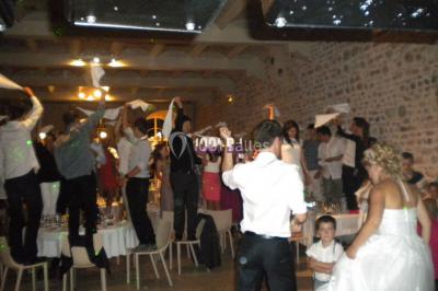 Un DJ mixe derrière une table éclairée de lumières LED violettes, avec un mur décoratif en arrière-plan.