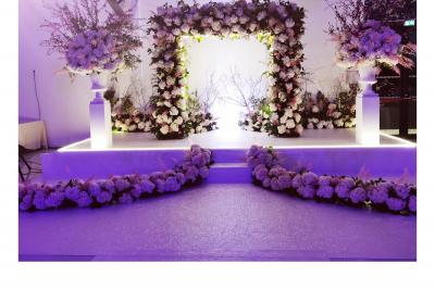 Un groupe de personnes en tenue traditionnelle célèbre un événement sous des lustres dans une grande salle éclairée.
