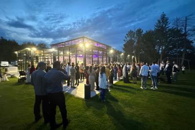 Un groupe de personnes en tenue traditionnelle célèbre un événement sous des lustres dans une grande salle éclairée.