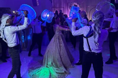 Un groupe de personnes en tenue traditionnelle célèbre un événement sous des lustres dans une grande salle éclairée.