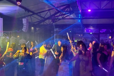 Un groupe de personnes en tenue traditionnelle célèbre un événement sous des lustres dans une grande salle éclairée.