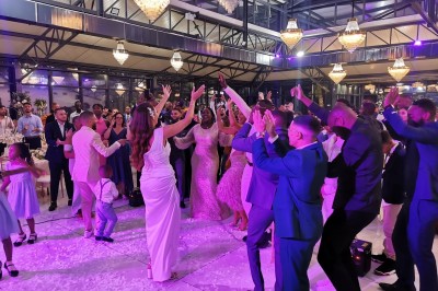 Un groupe de personnes en tenue traditionnelle célèbre un événement sous des lustres dans une grande salle éclairée.
