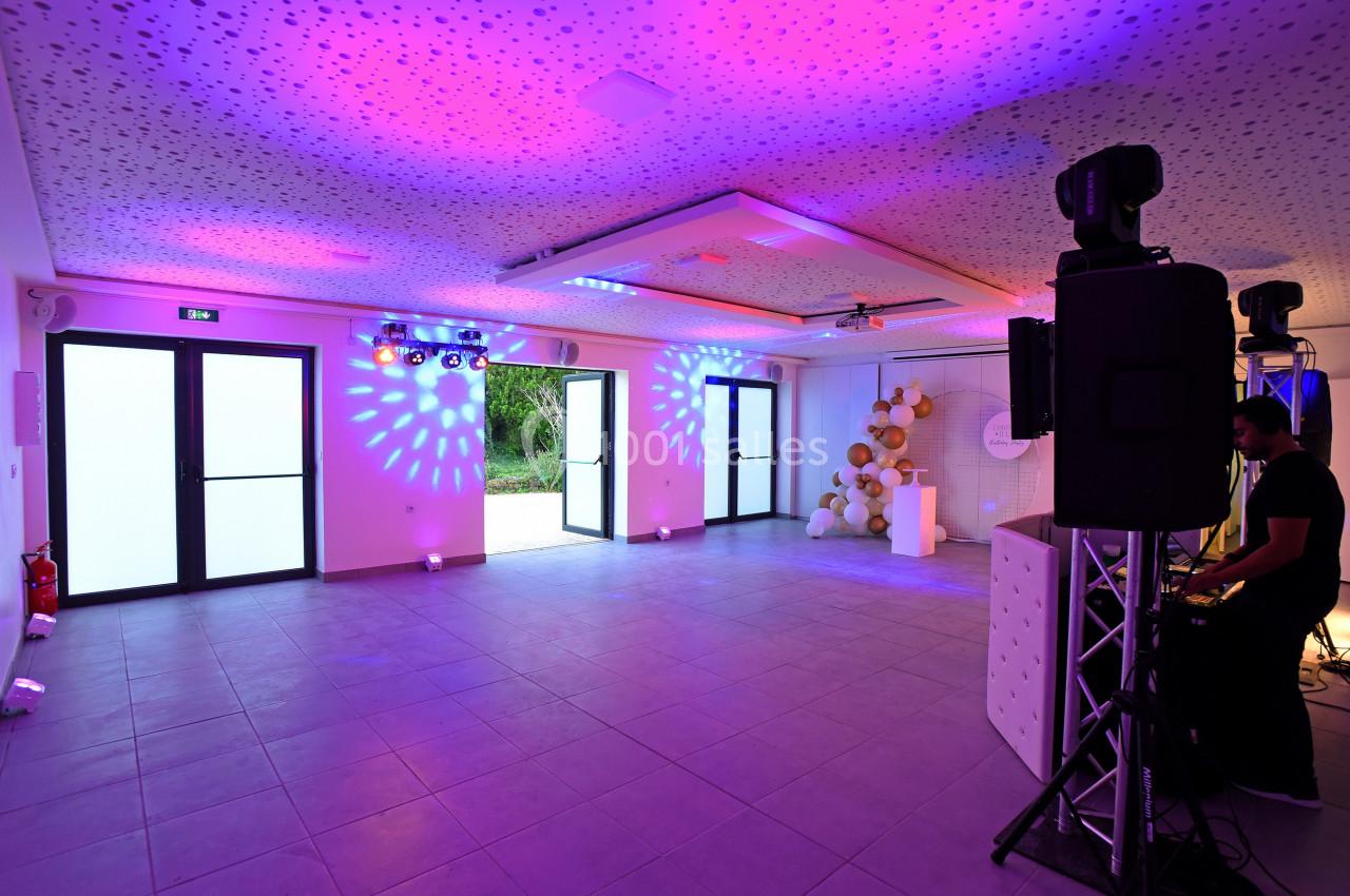 Salle de réception moderne avec éclairage coloré, décorations murales et équipement audio installé.