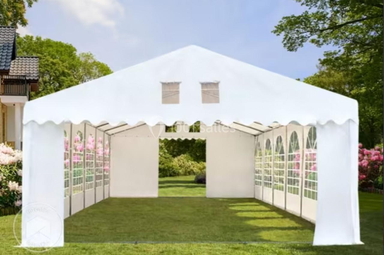 Tente blanche montée sur une pelouse, avec des parois latérales transparentes et un toit en pointe.