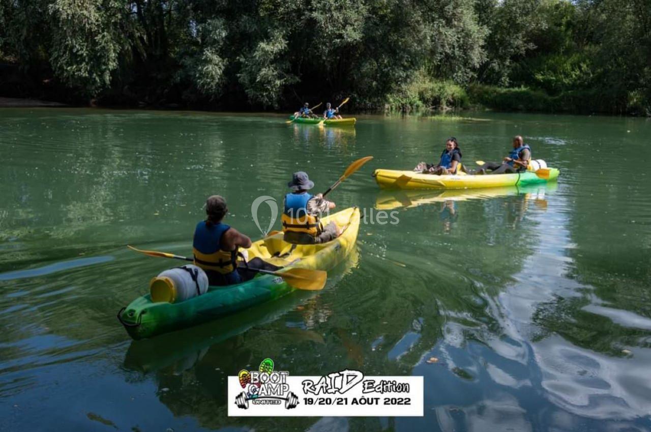 Des personnes pagayant en canoë sur une rivière entourée de végétation dense par une journée ensoleillée.