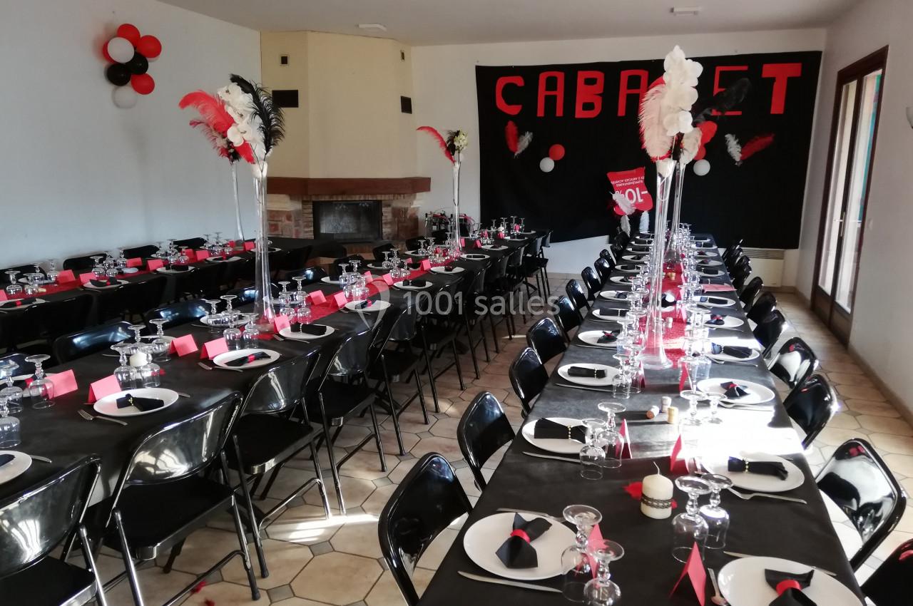 Salle décorée en noir, rouge et blanc avec tables dressées pour un événement sur le thème du cabaret.