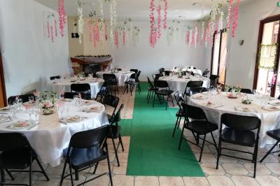 Des personnes assises en extérieur assistent à une cérémonie devant des tables décorées, près de chalets en bois.