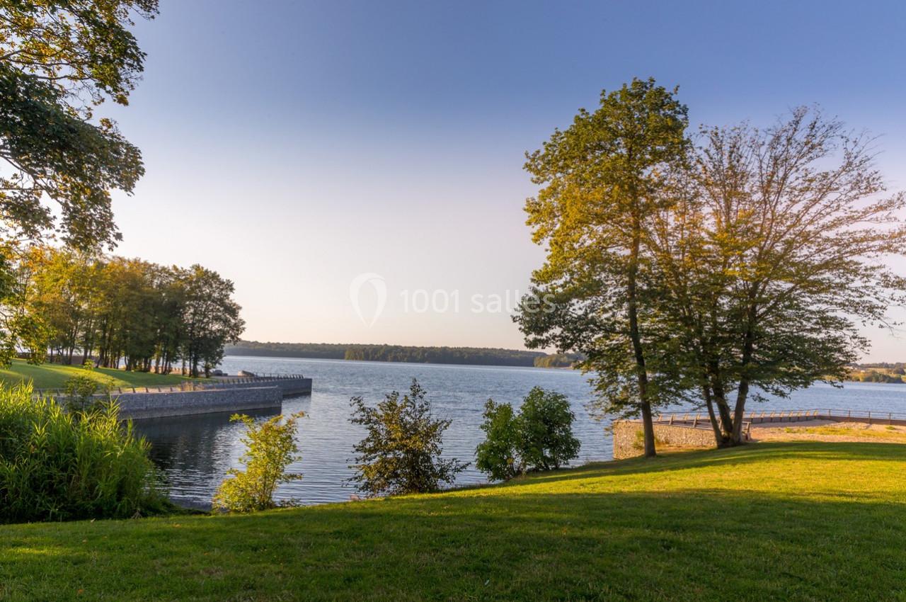 Photo Natura Parc #13 Vue d'un lac entouré d'arbres et de pelouses verdoyantes sous un ciel dégagé en fin de journée.
