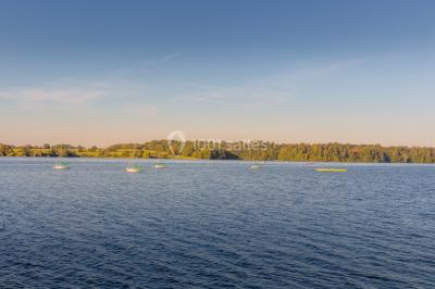 Miniature Natura Parc #14 Groupe de personnes rassemblées devant une maison en pierre avec un chapiteau, sur une pelouse par temps ensoleillé.