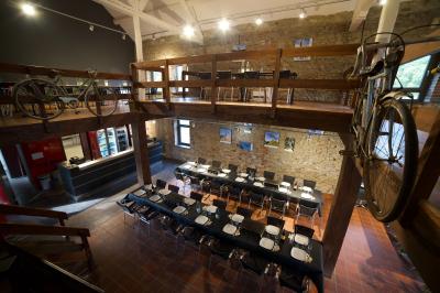 Miniature Natura Parc #15 Groupe de personnes rassemblées devant une maison en pierre avec un chapiteau, sur une pelouse par temps ensoleillé.