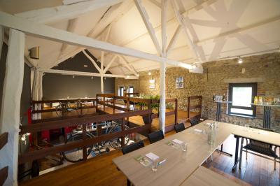 Miniature Natura Parc #21 Groupe de personnes rassemblées devant une maison en pierre avec un chapiteau, sur une pelouse par temps ensoleillé.