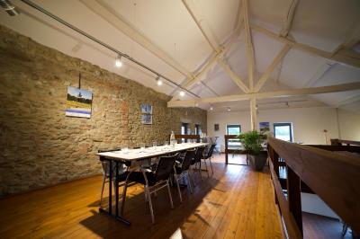 Miniature Natura Parc #23 Groupe de personnes rassemblées devant une maison en pierre avec un chapiteau, sur une pelouse par temps ensoleillé.