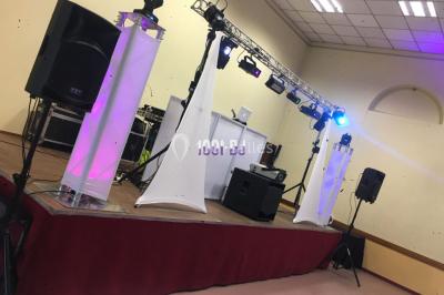 Miniature DJ Orgon (Bouches-du-Rhône) - TMD Musics #11 Salle de réception avec éclairage coloré, piste de danse vide et deux personnes debout près d'un bar lumineux.