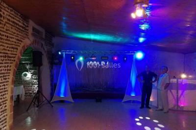 Miniature DJ Orgon (Bouches-du-Rhône) - TMD Musics #13 Salle de réception avec éclairage coloré, piste de danse vide et deux personnes debout près d'un bar lumineux.