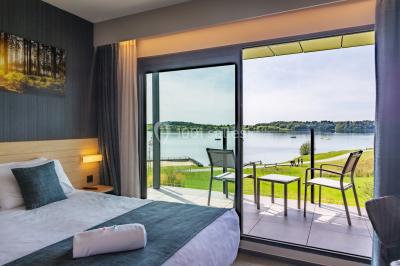 Miniature Location salle Froidchapelle (Hainaut) - Golden Lakes Hôtel #18 Terrasse en bois avec table et chaises, vue sur un jardin verdoyant et un lac au coucher du soleil.