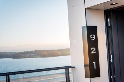 Miniature Location salle Froidchapelle (Hainaut) - Golden Lakes Hôtel #20 Terrasse en bois avec table et chaises, vue sur un jardin verdoyant et un lac au coucher du soleil.