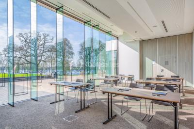Miniature Location salle Froidchapelle (Hainaut) - Golden Lakes Hôtel #2 Terrasse en bois avec table et chaises, vue sur un jardin verdoyant et un lac au coucher du soleil.