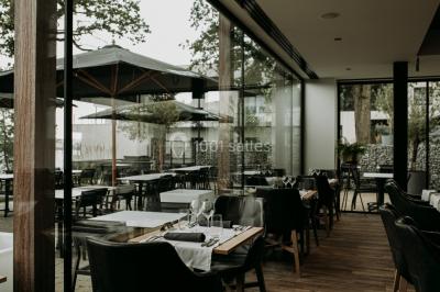 Miniature Location salle Froidchapelle (Hainaut) - Golden Lakes Hôtel #22 Terrasse en bois avec table et chaises, vue sur un jardin verdoyant et un lac au coucher du soleil.