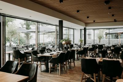 Miniature Location salle Froidchapelle (Hainaut) - Golden Lakes Hôtel #23 Terrasse en bois avec table et chaises, vue sur un jardin verdoyant et un lac au coucher du soleil.