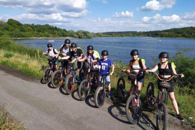 Miniature Location salle Froidchapelle (Hainaut) - Le Refuge du Badon #19 Dépliant sur des trottinettes électriques tout terrain posé sur une table avec viennoiseries et jus d'orange en arrière-plan.