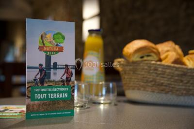 Miniature Location salle Froidchapelle (Hainaut) - Le Refuge du Badon #32 Dépliant sur des trottinettes électriques tout terrain posé sur une table avec viennoiseries et jus d'orange en arrière-plan.