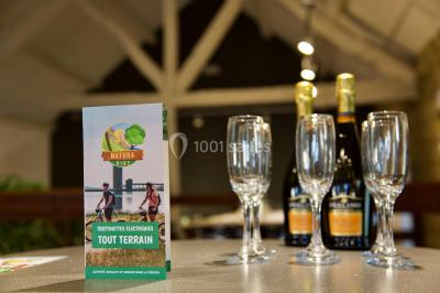Miniature Location salle Froidchapelle (Hainaut) - Le Refuge du Badon #30 Dépliant sur des trottinettes électriques tout terrain posé sur une table avec viennoiseries et jus d'orange en arrière-plan.