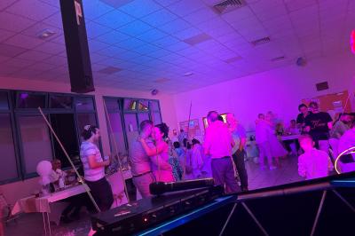 Miniature DJ Geville (Meuse) - Team MooMa Events #15 Des personnes dansent dans une salle éclairée par des lumières rouges, entourées de tables dressées pour un événement.