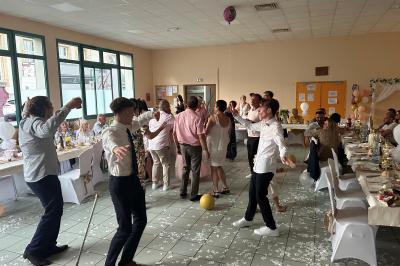 Miniature DJ Geville (Meuse) - Team MooMa Events #16 Des personnes dansent dans une salle éclairée par des lumières rouges, entourées de tables dressées pour un événement.