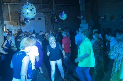 Miniature DJ Geville (Meuse) - Team MooMa Events #10 Des personnes dansent dans une salle éclairée par des lumières rouges, entourées de tables dressées pour un événement.