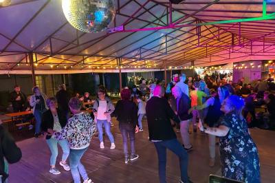 Miniature DJ Geville (Meuse) - Team MooMa Events #5 Des personnes dansent dans une salle éclairée par des lumières rouges, entourées de tables dressées pour un événement.