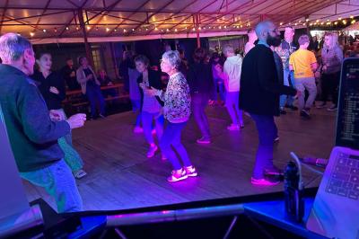 Miniature DJ Geville (Meuse) - Team MooMa Events #6 Des personnes dansent dans une salle éclairée par des lumières rouges, entourées de tables dressées pour un événement.