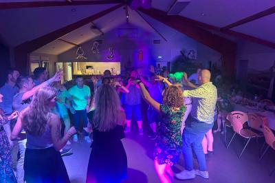 Miniature DJ Geville (Meuse) - Team MooMa Events #4 Des personnes dansent dans une salle éclairée par des lumières rouges, entourées de tables dressées pour un événement.