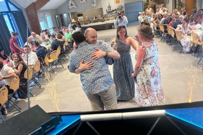 Miniature DJ Geville (Meuse) - Team MooMa Events #19 Des personnes dansent dans une salle éclairée par des lumières rouges, entourées de tables dressées pour un événement.