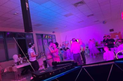 Miniature DJ Geville (Meuse) - Team MooMa Events #13 Des personnes dansent dans une salle éclairée par des lumières rouges, entourées de tables dressées pour un événement.