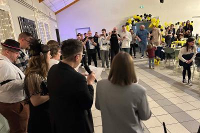 Miniature DJ Geville (Meuse) - Team MooMa Events #21 Des personnes dansent dans une salle éclairée par des lumières rouges, entourées de tables dressées pour un événement.