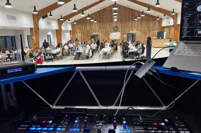 Miniature DJ Geville (Meuse) - Team MooMa Events #25 Des personnes dansent dans une salle éclairée par des lumières rouges, entourées de tables dressées pour un événement.