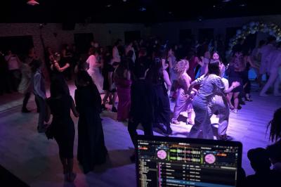 Miniature DJ Geville (Meuse) - Team MooMa Events #27 Des personnes dansent dans une salle éclairée par des lumières rouges, entourées de tables dressées pour un événement.