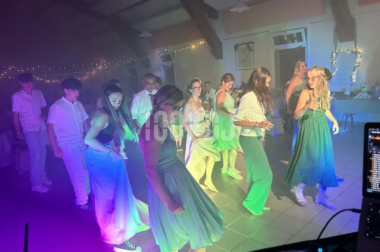 Des personnes dansent en groupe dans une salle éclairée par des lumières colorées, ambiance festive et décontractée.