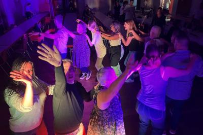 Miniature DJ Geville (Meuse) - Team MooMa Events #35 Des personnes dansent dans une salle éclairée par des lumières rouges, entourées de tables dressées pour un événement.