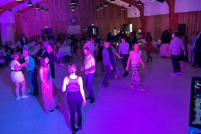 Miniature DJ Geville (Meuse) - Team MooMa Events #36 Des personnes dansent dans une salle éclairée par des lumières rouges, entourées de tables dressées pour un événement.