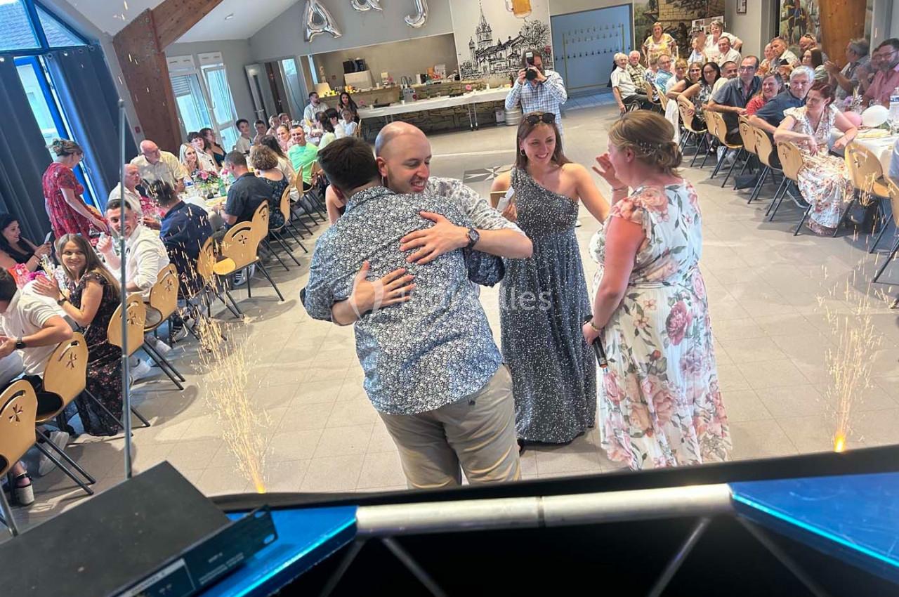 Des invités dansent et discutent dans une salle de réception décorée, entourés de tables occupées par d'autres convives.