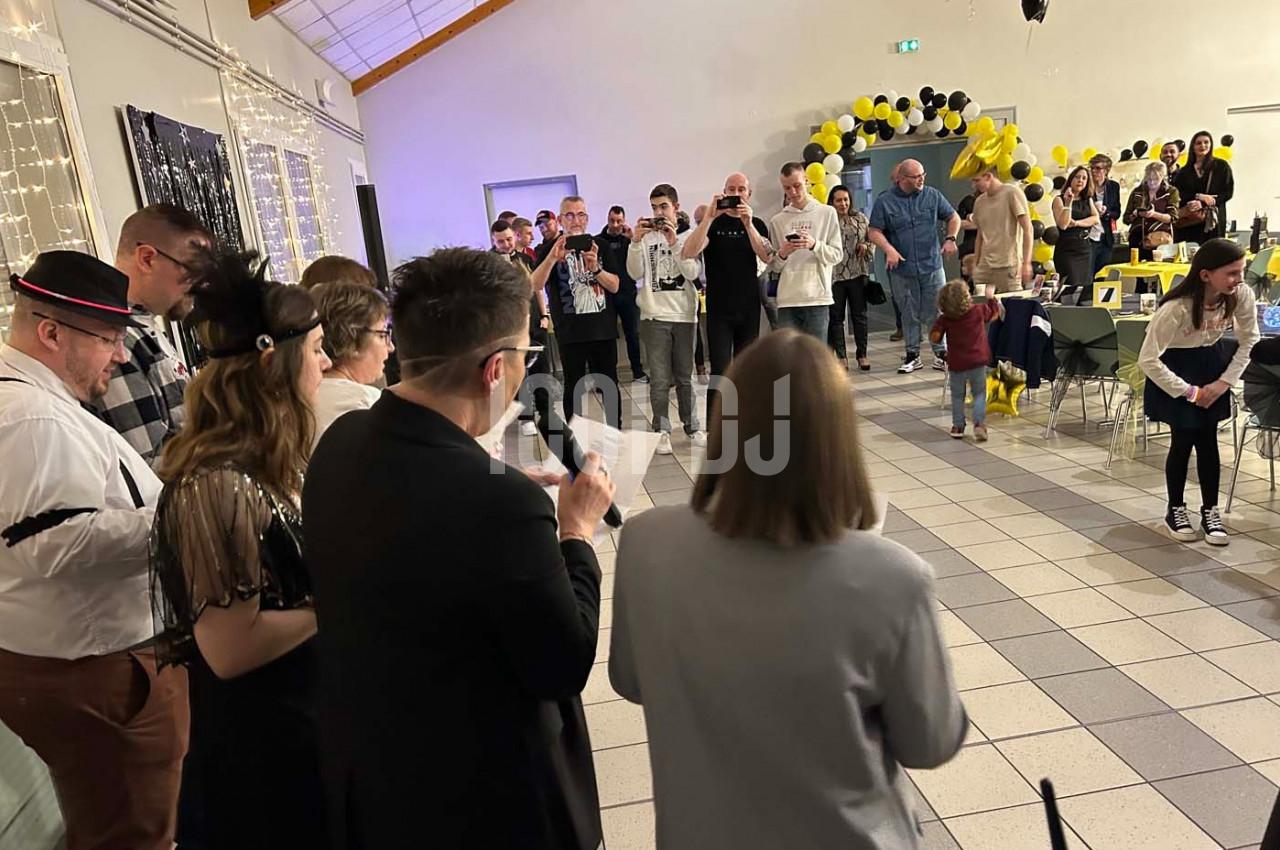 Groupe de personnes rassemblées dans une salle décorée de ballons noirs et jaunes, lors d'un événement festif.