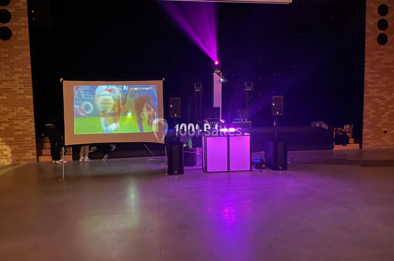 Installation de matériel audiovisuel avec écran de projection, éclairage coloré et équipement de sonorisation.