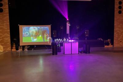 Équipement de sonorisation comprenant enceintes, projecteurs et consoles, installé sur une scène vide.