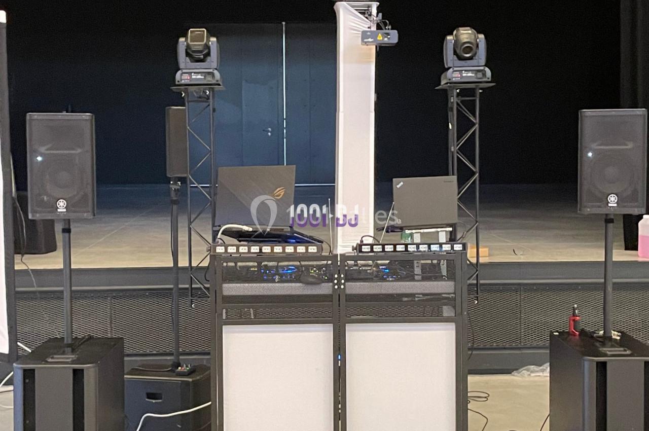 Équipement de sonorisation comprenant enceintes, projecteurs et consoles, installé sur une scène vide.