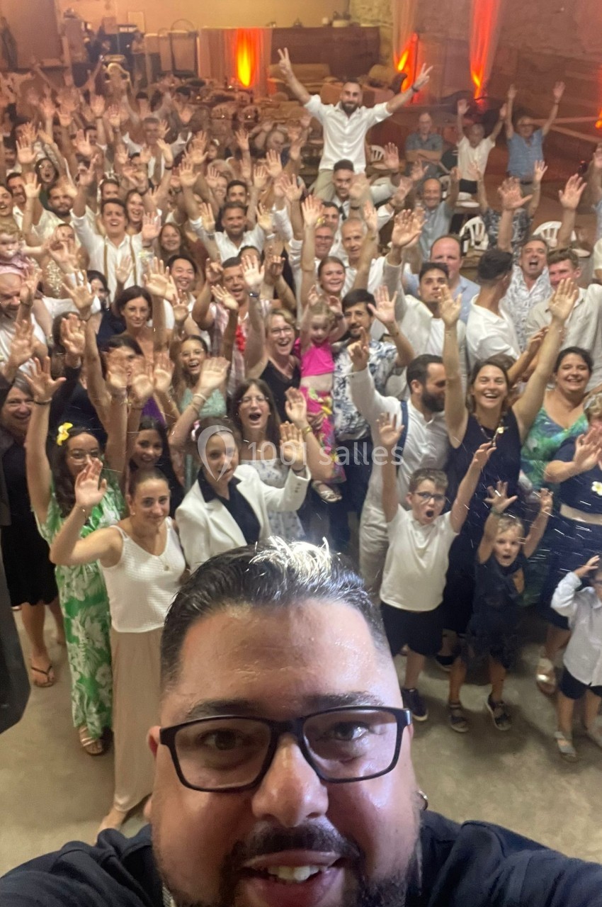Un groupe de personnes souriantes levant les bras lors d'un événement festif dans une salle éclairée.