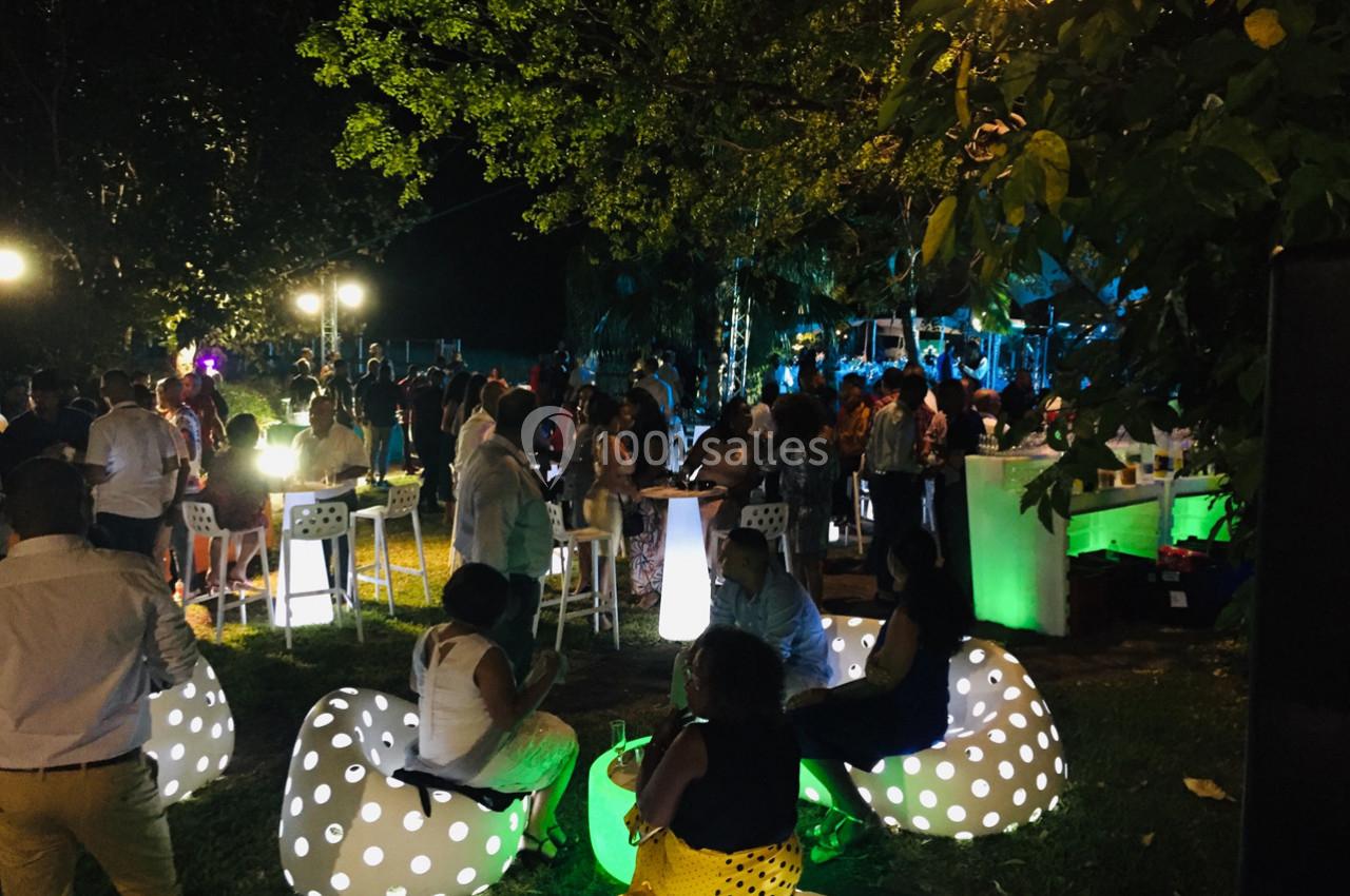Groupe de personnes réunies en soirée extérieure, éclairée par des lumières colorées et des sièges lumineux.