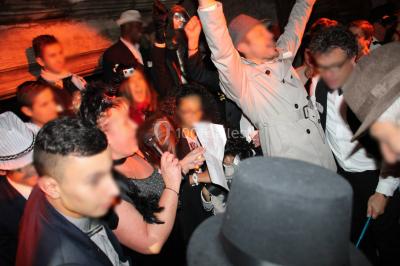 Ours en peluche avec un nœud rose devant un présentoir de cupcakes décorés dans un décor rose et lumineux.